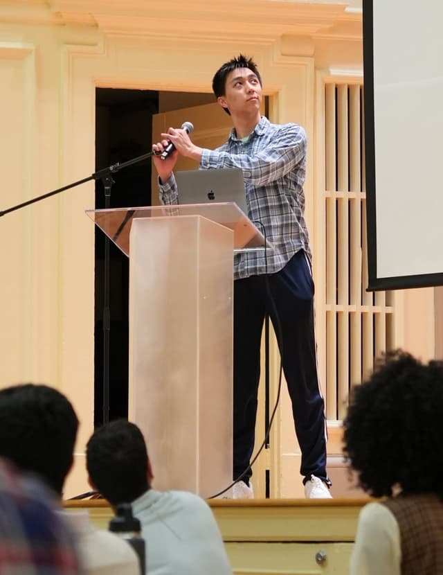 Justin Jin speaking at podium - Business leader and startup founder